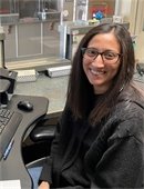 woman with dark hair and glasses sitting at a desk