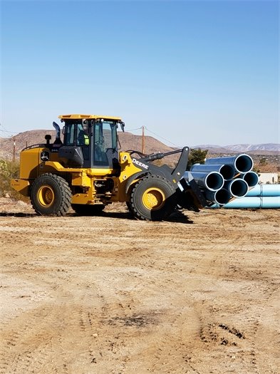 tractor carrying large water pipes